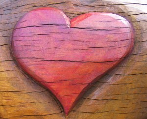 Red heart carving in piece of brown wood
