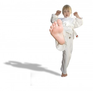 young blonde boy in karate uniform kicking his foot towards the camera