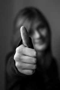 black and white image of woman holding a thumbs up to the camera
