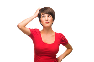 short-haired woman in bright red shirt scratching her head