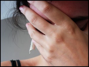 closeup of woman hiding her face behind her hand