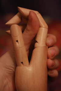 Human hand holding wooden model of a hand