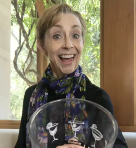 Martha Beck holding empty cocktail glass towards the camera