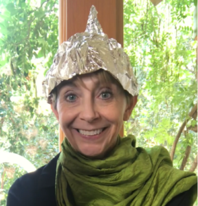 Martha Beck smiling at camera wearing tinfoil hat
