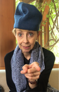 Martha Beck wearing loose-fitting blue hat and pointing at the camera