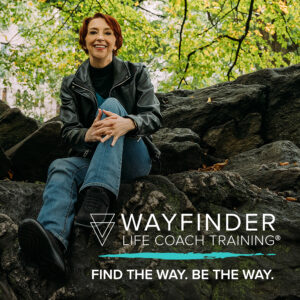Martha sitting under a canopy of trees on a large rock with the words Wayfinder Life Coach Training Find the Way. Be the Way.