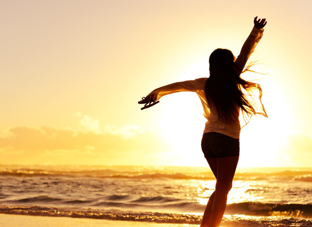 silhouette of long-haired woman dancing on beach at sunset