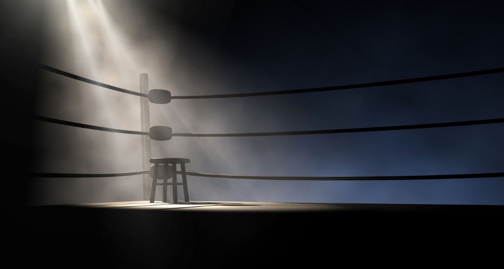 dark empty boxing ring with spotlight on a stool in the corner