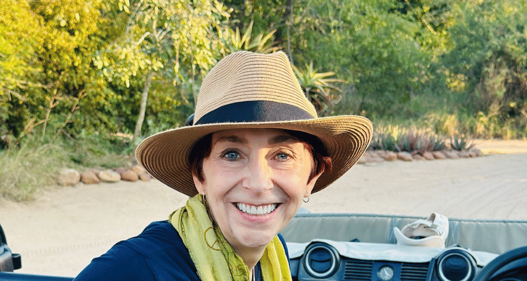 Martha smiling broadly with a hat on in an open Land Rover.