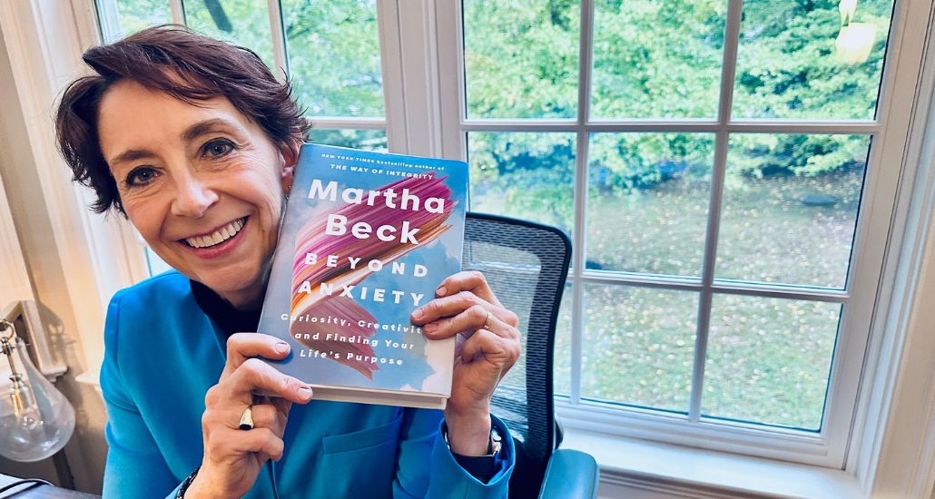 Martha smiling holding her new book Beyond Anxiety.