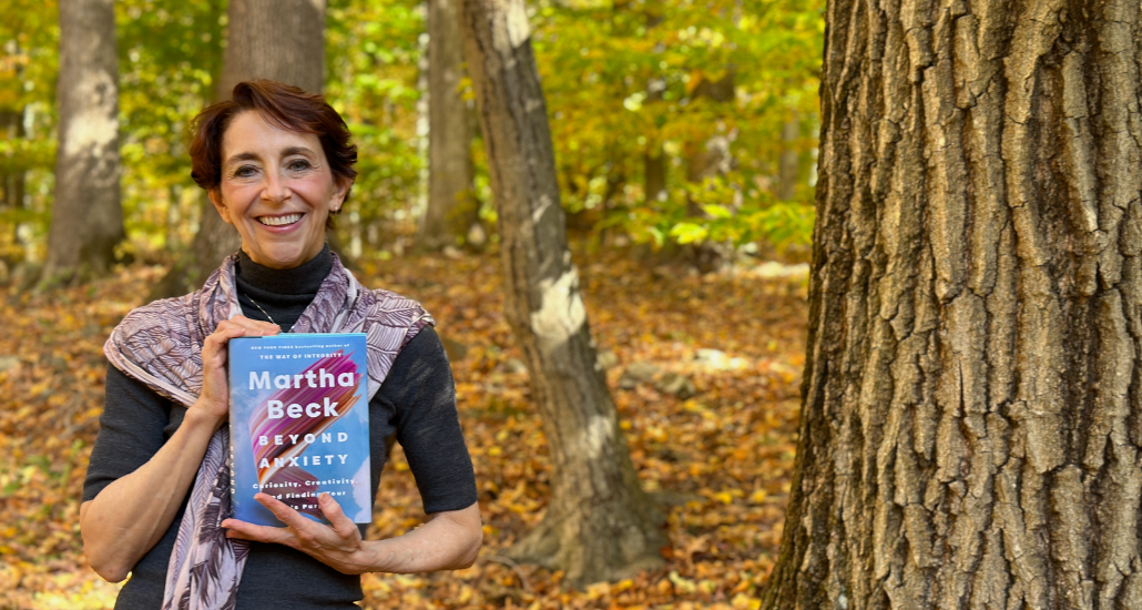 Martha holding her book Beyond Anxiety in a Fall Forest